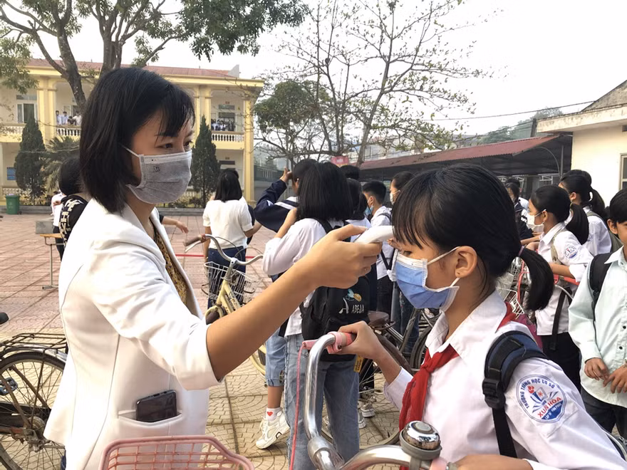 Giáo viên đo nhiệt độ cho học sinh trong ngày tới trường tại Vĩnh Phúc.