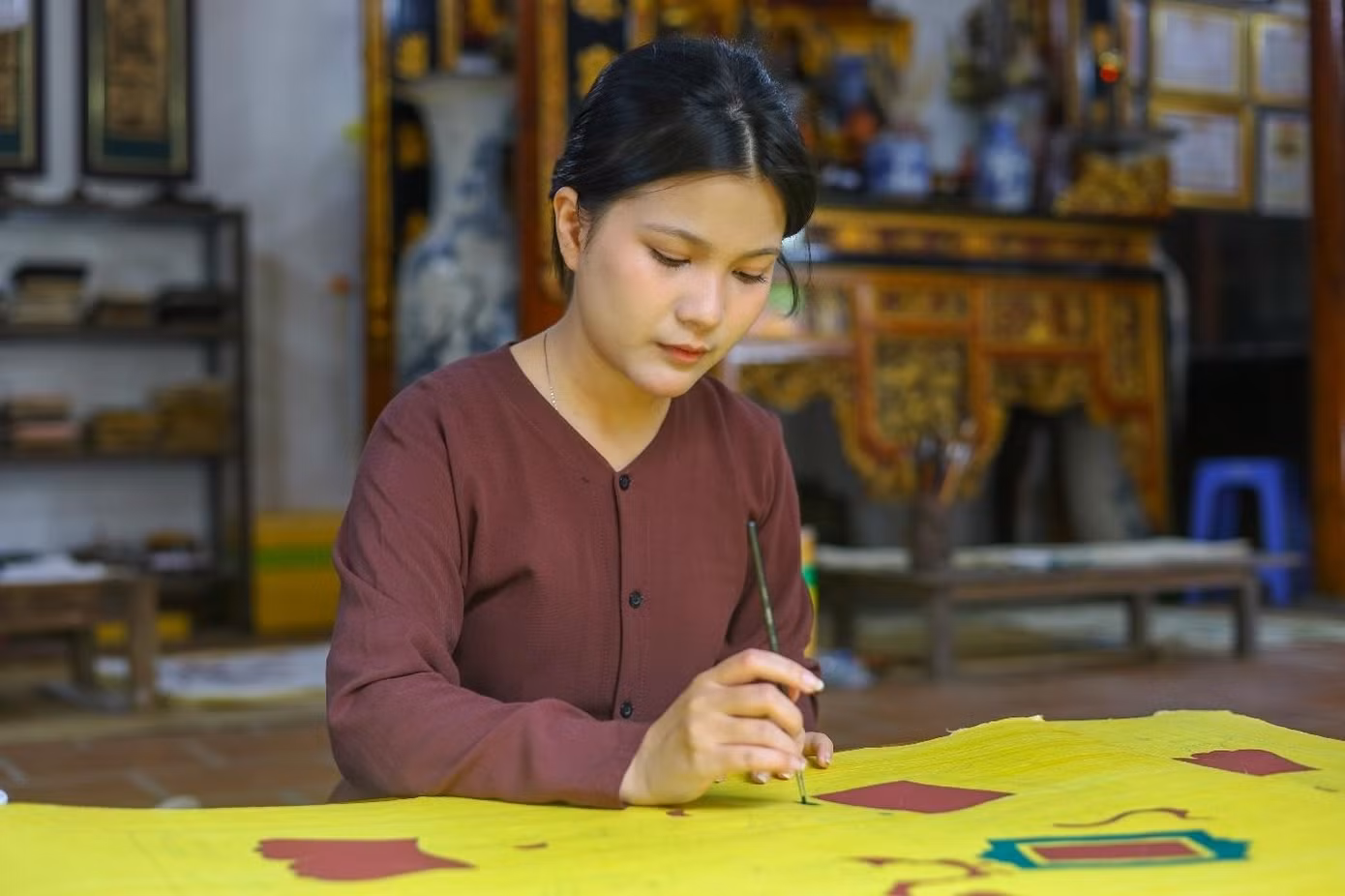 Cô nàng còn tham gia vào công đoạn tô màu cho những bức tranh ở khổ lớn, bước này đòi hỏi sự tập trung cao độ trong công đoạn vẽ nét, thổi hồn vào từng chi tiết trên nền giấy điệp vàng óng đặc trưng của tranh Đông Hồ. (Ảnh: Minh Hiền)