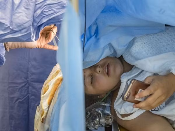 Jess Banik đang sử dụng điện thoại trong khi các bác sĩ đang tiến hành ca phẫu thuật não cho cô