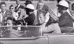 Tổng thống John F. Kennedy vẫy tay chào khi đang ngồi cùng đệ nhất phu nhân Jacqueline Kennedy trong chiếc xe được hộ tống qua Dallas ngày 22/11/1963.