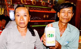 Vợ chồng ông Nguyễn Văn Tổng bên chai thuốc trừ sâu mà Kiệt dùng để tự tử