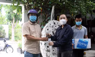 Chậu lan rừng phi điệp được Thảo (áo đen) bán cho khách hàng với giá... 2 thùng nước lọc. Toàn bộ số nhu yếu phẩm này sẽ được hỗ trợ cho các chốt kiểm dịch và khu phong tỏa. Ảnh: Giang Thanh