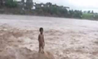 Cậu bé bốn tuổi đứng giữa dòng nước lũ