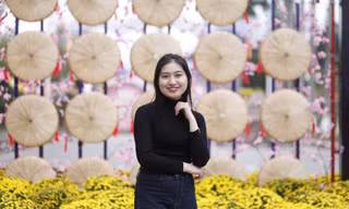 Các bạn trẻ chụp ảnh lưu niệm tại mô hình nón quai thao ở đường hoa Tết. Ảnh: Nguyễn Thắng.