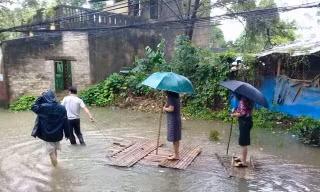 Chủ tịch phường đứng trên bè cho người kéo qua vùng nước ngập
