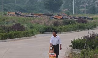 Một ông bố đưa con đi dạo qua đoạn đường có rất nhiều quan tài mới bị đập vỡ ở tỉnh An Huy.