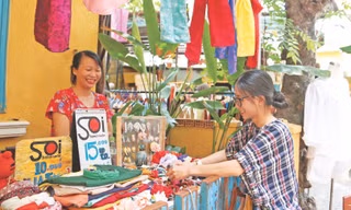 Chị Trương Nguyễn Hoài An, người sáng lập Chợ phiên thủ công (bên phải) hỗ trợ các cư dân của xóm bày biện, sắp xếp hàng hóa Ảnh: Giang Thanh 