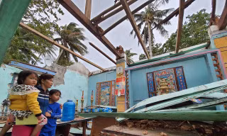 Chị Nguyễn Thị Sương Mai (trú thôn Hòa Lợi, Thị xã Sông Cầu) đứng ôm hai con nhỏ bên căn nhà bị tốc mái, đổ nát do bão...