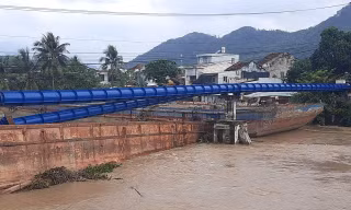 Một chiếc sà lan đã đâm gãy ống nước bắc qua sông Cái. Ảnh L.H