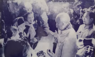 Trong ảnh, bà Diên quàng cổ chiếc khăn màu trắng