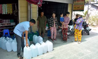 Ông Lê Thành Văn, Trưởng ấp Thanh Tùng (xã Biển Bạch, Thới Bình, Cà Mau) phát nước uống miễn phí từ nhà hảo tâm cho bà con để giải cơn khát. Ảnh: Tân Lộc