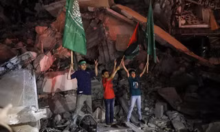Trẻ em Palestine vẫy cờ Palestine và Hamas khi đang đứng trên đống đổ nát để bày tỏ vui mừng với thỏa thuận ngừng bắn ở Gaza ngày 21/5. Ảnh: AP