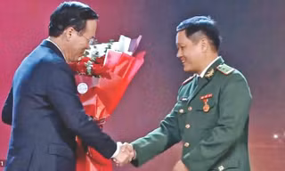 Trung tá Đặng Hùng Cường (bìa phải) nhận hoa chúc mừng mô hình “Lũy tre biên giới Việt” từ Chủ tịch nước Võ Văn Thưởng. Ảnh: Duy Chiến