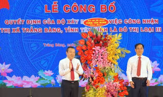 Bí thư Thị ủy Trảng Bàng Đoàn Minh Long (phải) nhận hoa chúc mừng tại buổi lễ. Ảnh: Y.N