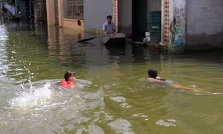 Hai đứa trẻ bơi giữa đường ngập lụt ở xóm Bến Vôi, thôn Cấn Hạ (xã Cấn Hữu, Quốc Oai, Hà Nội). Ảnh: Trường Phong