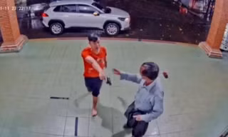 Người mặc áo đỏ cầm vật giống cây súng chĩa vào hai phụ nữ đối diện - ảnh chụp màn hình