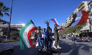 Những người ủng hộ chính phủ ông Bashar al-Assad tại Damascus (Syria) vẫy cờ Nga, Iran, Syria nhằm động viên tinh thần binh sĩ nước này sau sự kiện bị Mỹ tấn công. Ảnh: AP