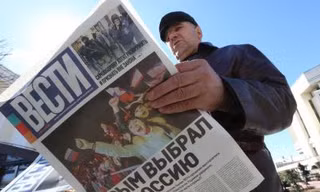 Một người đàn ông đọc tờ báo có tựa đề "Crimea chọn Nga" ở Simferopol, Crimea