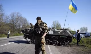 Một lính Ukraine đứng trước xe tăng ở trạm kiểm soát tại làng Malinivka, Slaviansk, đông Ukraine 
