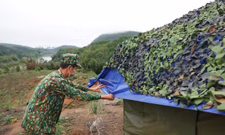 Trung tá quân nhân chuyên nghiệp Bùi Văn Bách tháo nước đọng trên mái che lán dã chiến Ảnh: Nguyễn Minh