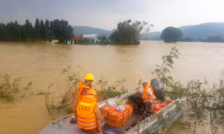 Công an huyện Tuy Phước dùng ca nô để hỗ trợ lương thực cho người dân bị nước lũ cô lập. Ảnh: Trương Định
