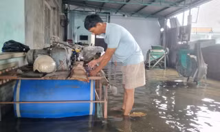 Người dân vùng ngập tự chế bè nổi bằng thùng nhựa chứa cả tấn đồ trên nước lũ