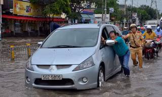 Một CSGT dầm mình trong nước nỗ lực đẩy chiếc xe ô tô bị chết máy.
