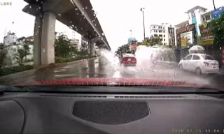 Chiếc sedan lao nhanh trên đường mưa, bắn nước lên người đi xe máy