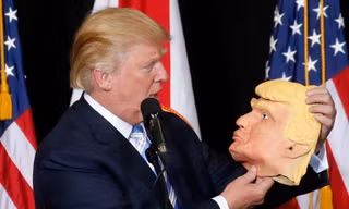 Ông Donald Trump, ứng viên đảng Cộng hòa, cầm trên tay chiếc mặt nạ hình ông tại điểm vận động tranh cử ở Sarasota, Florida tối ngày 7/11 (giờ địa phương).