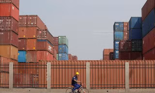 Công nhân đi ngang một trung tâm kho vận ở cảng Thiên Tân, Trung Quốc hôm 16/5. Ảnh: Reuters