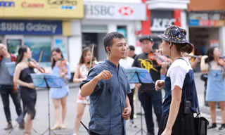 Lưu Quang Minh đang chỉ đạo dàn nhạc biểu diễn trên phố đi bộ Hà Nội.