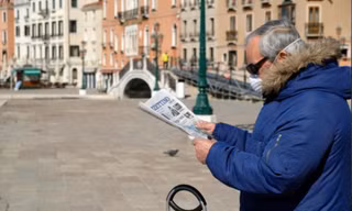 Một người dân đọc báo ở Venice (Ý) ngày 15/3. Ảnh: Reuters
