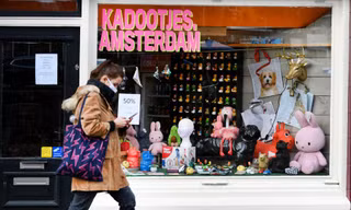 Một người phụ nữ đeo khẩu trang đi bộ ở Amsterdam (Hà Lan). Ảnh: Reuters