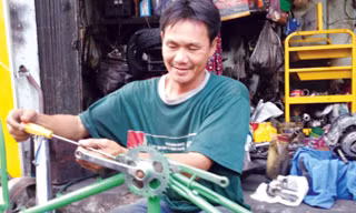 Anh Lê Văn Thái lắp ráp xe đạp cũ tặng người nghèo. Ảnh: Trọng Thịnh.