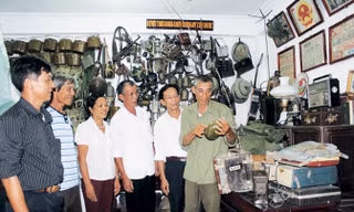 Ông Bùi Đình Thu (mặc áo lính) giới thiệu các kỷ vật chiến tranh cho khách tham quan.