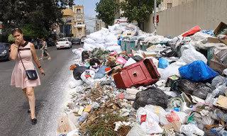 Một phụ nữ bịt mũi đi qua bãi rác thải tạm thời ở Jdeideh, phía đông bắc thủ đô Beirut của Li-băng. Ảnh: Getty Images.