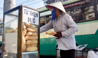 Một người mua ve chai đang lấy bánh mì từ thiện.