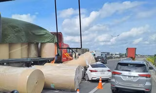 Nhiều cuộn giấy trên xe đầu kéo rơi xuống đường, đè trúng ô tô con