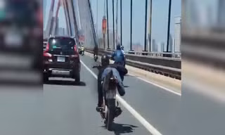 Thanh niên nằm trên yên điều khiển xe máy, phóng vun vút qua cầu Nhật Tân