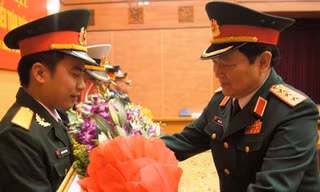 Thượng tướng Ngô Xuân Lịch (bên phải), Bí thư T.Ư Đảng, Chủ nhiệm Tổng cục Chính trị trao bằng khen và tặng hoa chúc mừng Trung úy Hoàng Văn Đông, tháng 3/2014. ảnh: NGUYỄN MINH