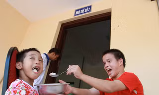 Hai em nhỏ tự đút cơm cho nhau ăn rất ngon lành. Ảnh: Minh Đức