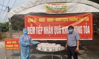 Chị Lê Thị Minh (bìa trái) mang suất ăn đến khu vực phong tỏa Ảnh: H.C 