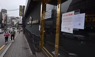 Một cặp đôi đeo khẩu trang bước ngang một hộp đêm đóng cửa ở Itaewon hôm 10/5. Ảnh: Getty Images.