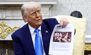 Tổng thống Mỹ Donald Trump giơ bài viết có hình ảnh vụ chôn tập thể ở Congo trong cuộc gặp Tổng thống Nam Phi. (Ảnh: Reuters)