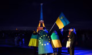 Người Ukraine cầm cờ Ukraine và châu Âu khi Tháp Eiffel được thắp sáng bằng màu cờ của Ukraine vào dịp tròn 3 năm nổ ra cuộc xung đột. (Ảnh: AP)