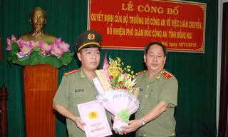 Thiếu tướng Nguyễn Thanh Nam (bìa phải) trao quyết định và tặng hoa chúc mừng Trung tá Lê Hoàng Ngân. Ảnh: Báo Đồng Nai 