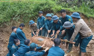 Chiến sỹ lực lượng vũ trang đưa bom xuống hố để hủy nổ. Ảnh: TTXVN phát.