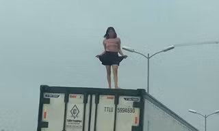 Người phụ nữ mặc váy ngắn, ca hát nhảy múa trên nóc thùng xe container.