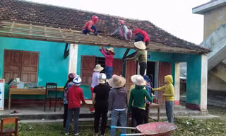 Sau bão, nữ giáo viên leo nóc nhà lợp ngói cho trường