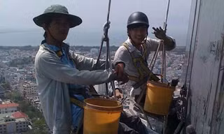 Những người thợ lau kính phải cheo leo giữa không trung để mưu sinh - Ảnh: Bảo Nguyên 